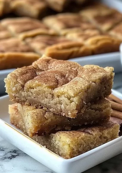 Chewy Snickerdoodle Cookie Bars topped with cinnamon sugar on a plate.