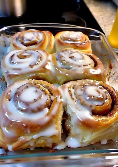 Delicious classic cinnamon rolls topped with creamy icing on a wooden table