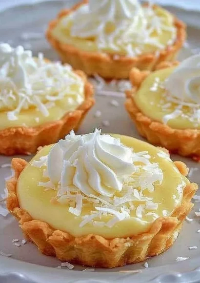Delicious coconut cream tarts topped with whipped cream and toasted coconut flakes