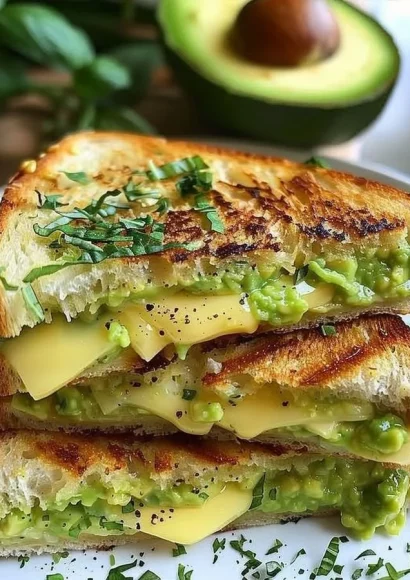 Creamy avocado grilled cheese sandwich with melting cheese and fresh avocado slices.