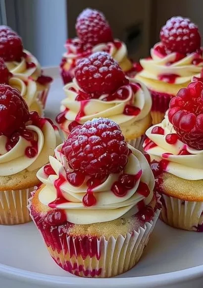 Heavenly raspberry cheesecake cupcakes topped with fresh raspberries and cream.