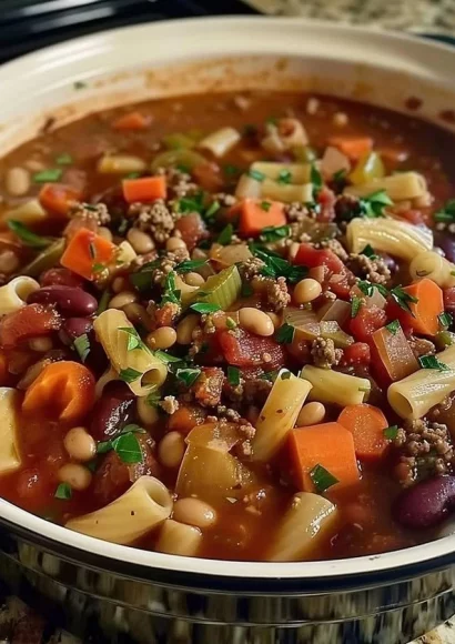 A warm bowl of Pasta Fagioli garnished with herbs and served with crusty bread.