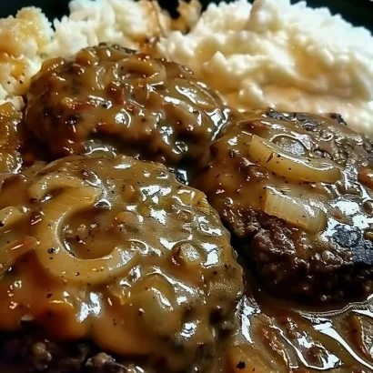 Smothered hamburger steak with gravy and sides on a plate